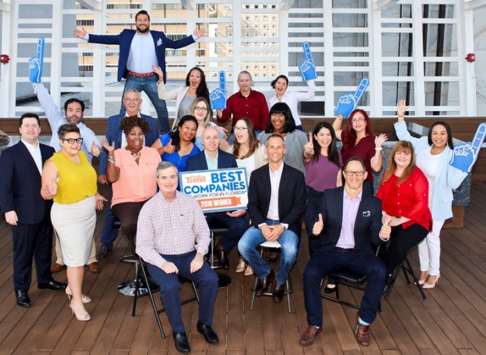 Image depicts Bast Amron team holding sign reading Florida Trend Best Companies To Work For In Florida