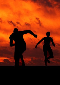 Image is a silhouette man and woman running with a spectacular sunrise behind them.